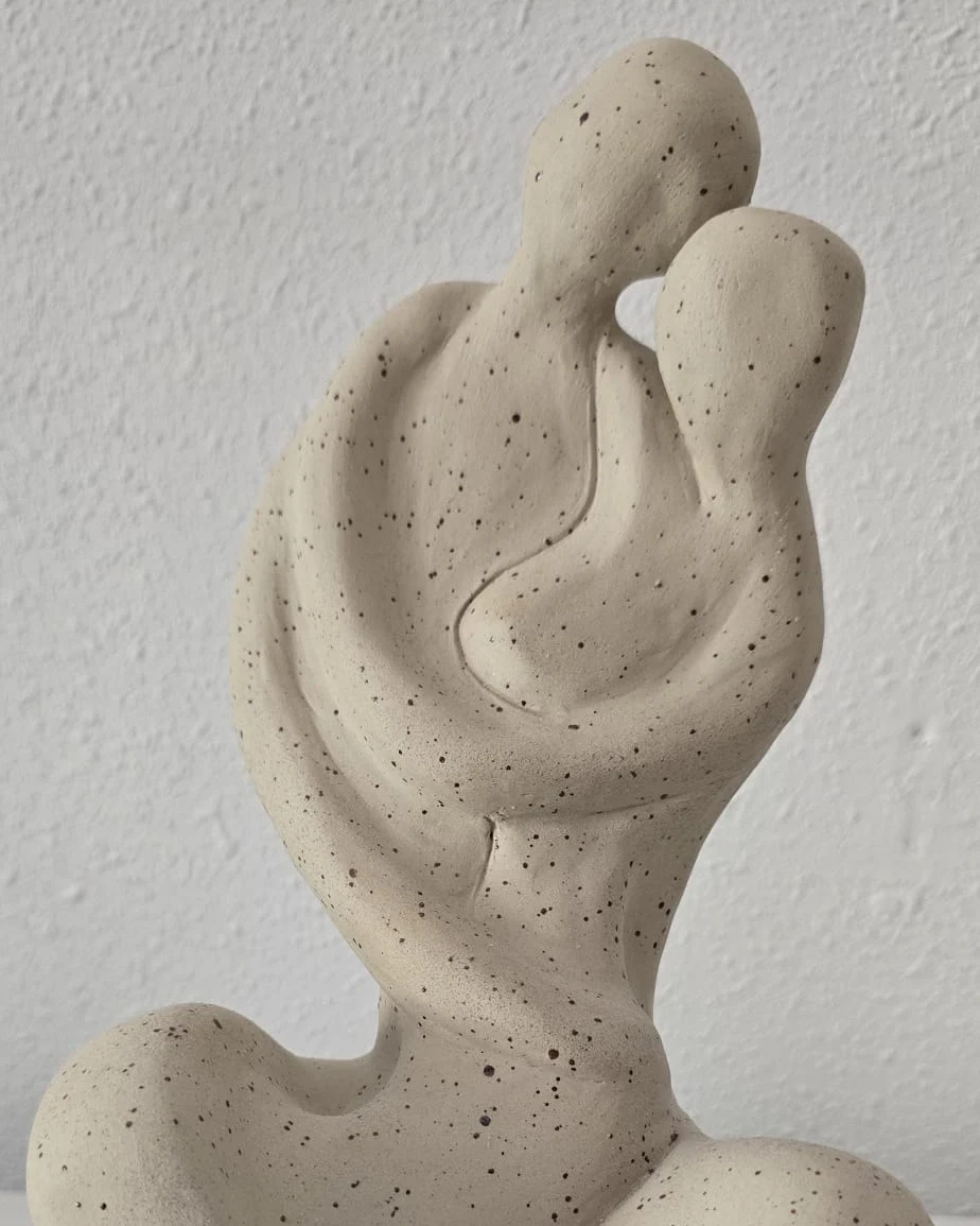 Sculpture blanche abstraite de deux figures enlacées.
